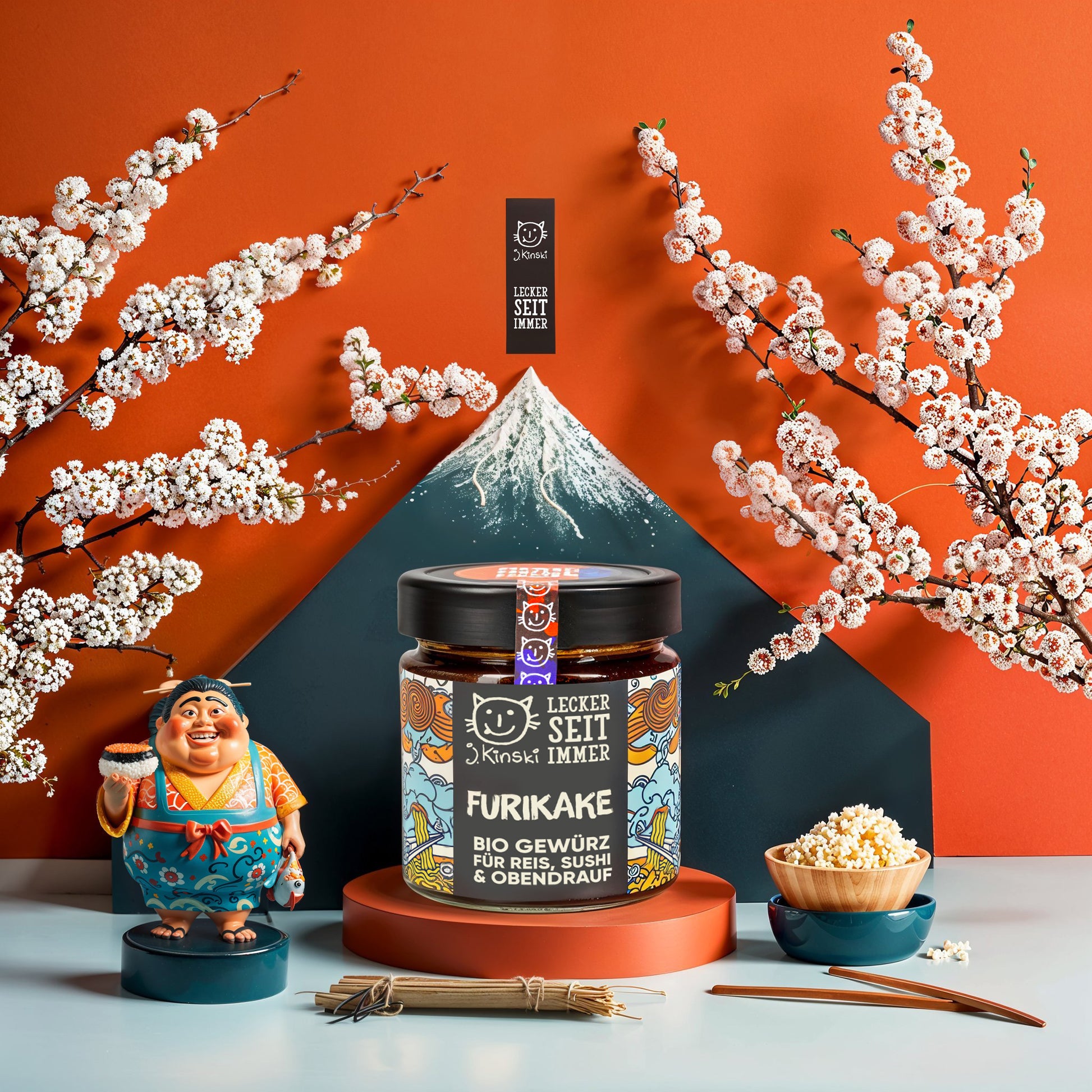 Roter Hindergrund mit Kirschblüten Deko, Furikakegewürz daneben eine Asiatische Figur