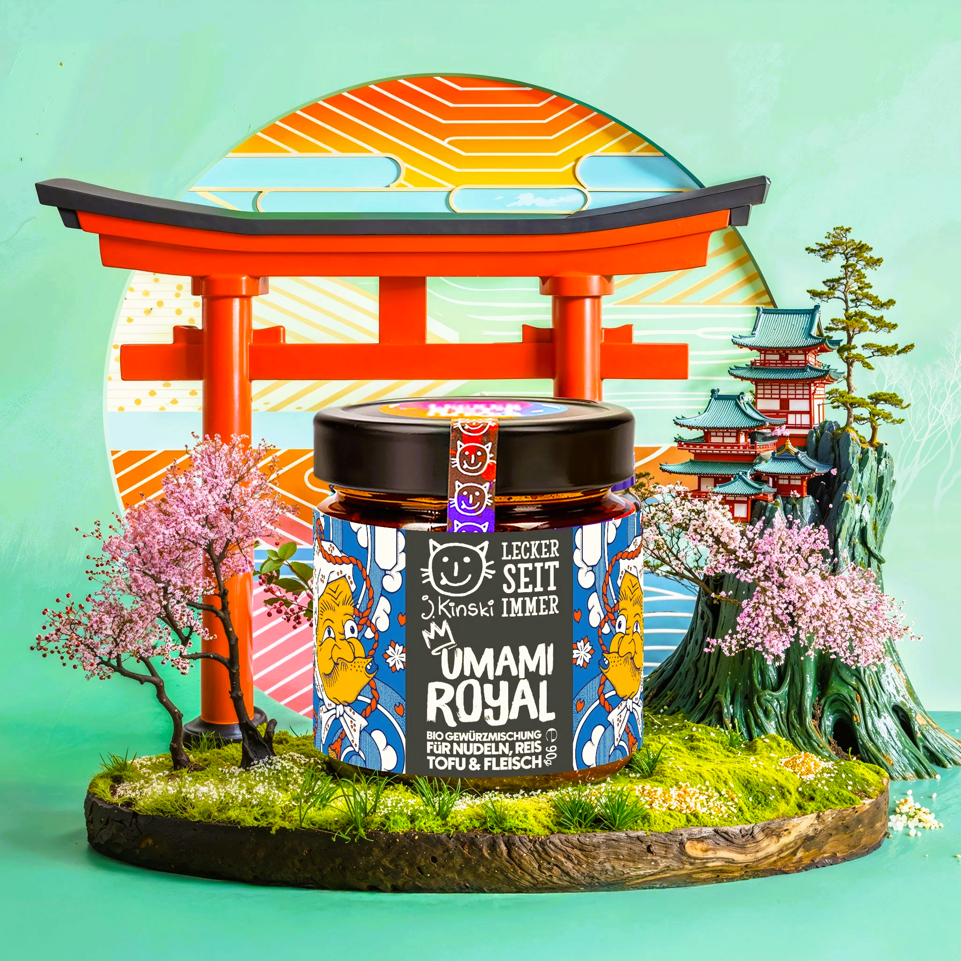 Ein Glas mit dem Produkt "Umami Royal Bio Gewürzmischung" steht im Zentrum des Bildes.Das Glas hat ein buntes Etikett mit japanischen Schriftzeichen und Illustrationen.
 Der Hintergrund ist eine stilisierte, zweidimensionale Landschaft, die an Japan erinnert. Ein rotes Torii-Tor, ein typisches japanisches Bauwerk, steht im Hintergrund. Im Hintergrund sind japanische Gebäude, möglicherweise Pagoden, zu sehen. Rosa Blüten, Kirschblüten,